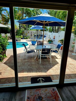 Un patio con piscina, sillas de descanso y sombrillas.