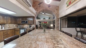 Une cuisine spacieuse dotée de plans de travail en granit, d’un grand îlot central et d’éléments décoratifs en pierre.