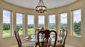 A dining room with a round table, chairs, and a chandelier.