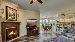 A living room with a fireplace, TV, dining area, and kitchen.