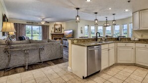 A spacious living area with a sofa, a fireplace, and a kitchen with granite countertops and white cabinets.
