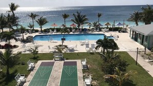 Ett poolområde med en shuffleboard-bana, solstolar och utsikt över havet.