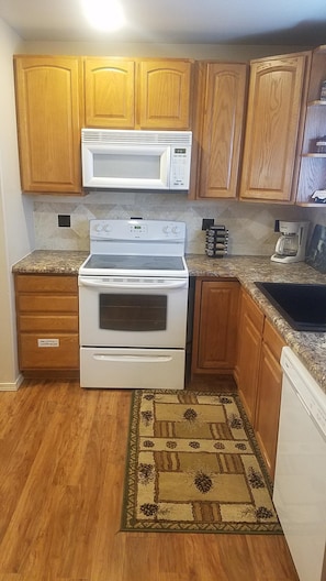 Una cocina con armarios de madera, microondas, estufa y lavavajillas.