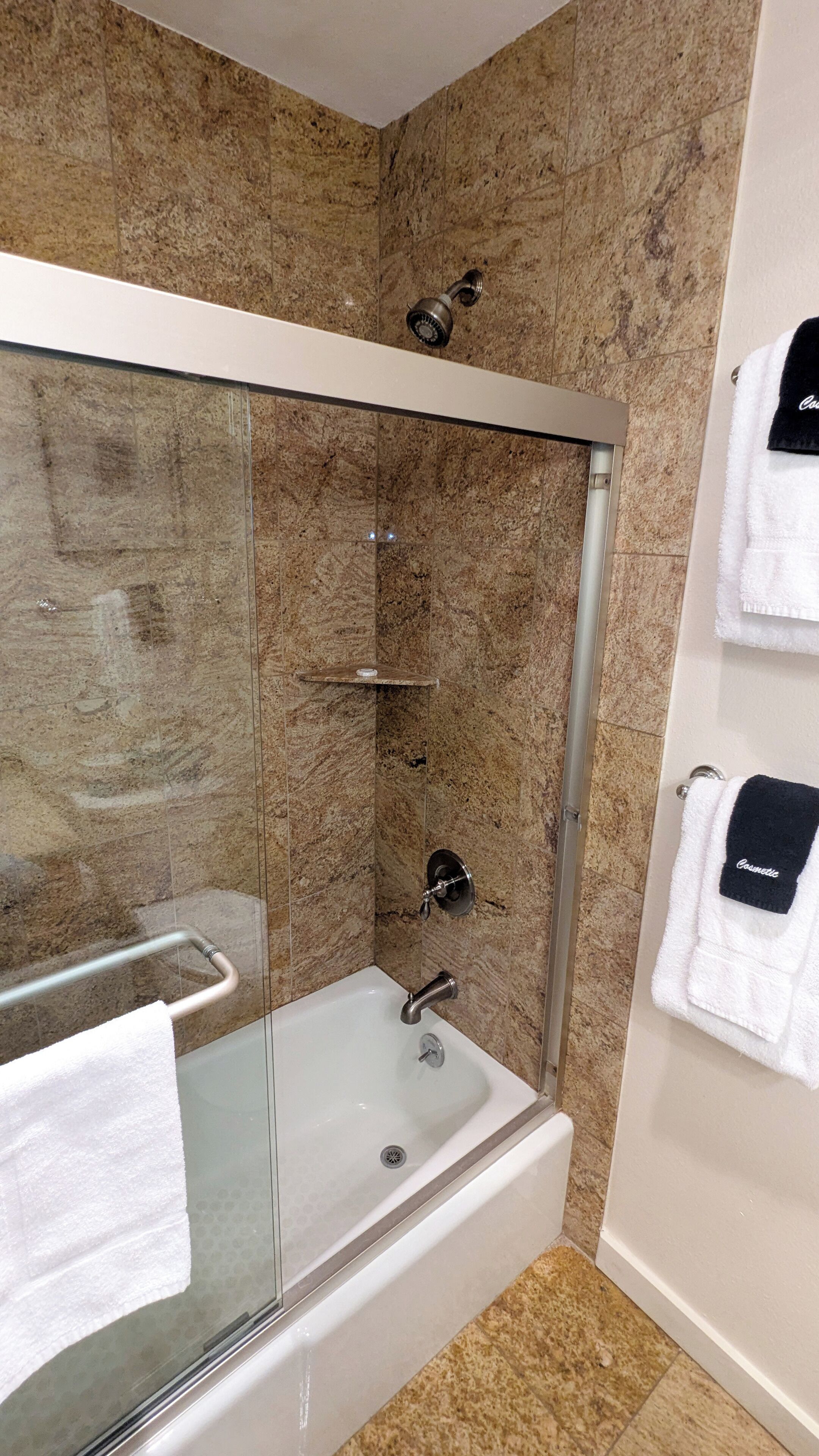 A modern bathroom with a glass-enclosed shower, a bathtub, and a towel rack with two towels.