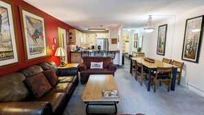 A living room with a sofa, a coffee table, and a dining area with a table and chairs.