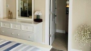 A bedroom with a bed, dresser, mirror, and a hallway leading to a bathroom. -  Make Memories at Barefoot Daze (Kitty Hawk)