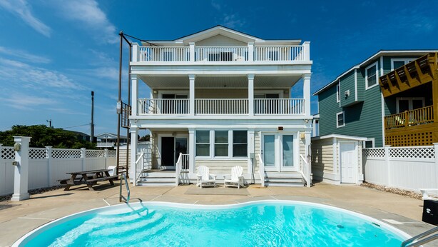 A two-story house with a swimming pool, a picnic table, and two Adirondack chairs. -  Make Memories at Barefoot Daze (Kitty Hawk)