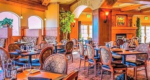 Ein Restaurant mit Holzkasteln, Tischen und Stühlen. Es gibt Pflanzen und einen Kamin.