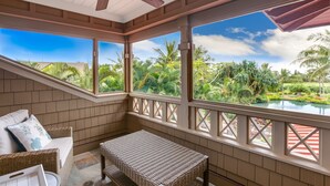A covered outdoor area with wicker furniture, a bench, and a view of a pool and tropical vegetation. - Hale Wai'olu by Alekona Kauai: Luxury 3br ocean view home in Kukuiula, AC, private pool, fire pit (Koloa)