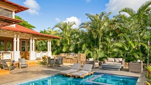 A pool area with lounge chairs and a stone wall. - Hale Wai'olu by Alekona Kauai: Luxury 3br ocean view home in Kukuiula, AC, private pool, fire pit (Koloa)