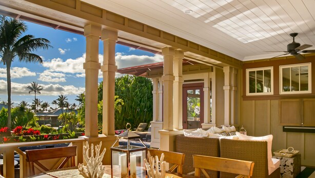A covered outdoor seating area with a wooden table, chairs, and a lantern. - Hale Wai'olu by Alekona Kauai: Luxury 3br ocean view home in Kukuiula, AC, private pool, fire pit (Koloa)