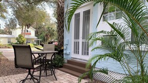 A patio with a table and chairs, a white door, and a small garden area with a palm tree. - Relax at the Island Escape in Downtown Melbourne, minutes from beautiful beaches (Melbourne)