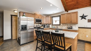 A modern kitchen with a central island, stainless steel appliances, wooden cabinets, and a star decoration on the wall. - “Mountain Escape-7BR, Game Room, Fire Pit Close to Skiing and Trails!” (Lake Harmony)