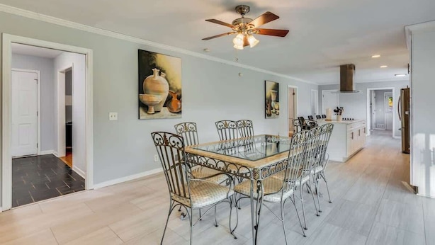 A dining area with a glass-top table and metal chairs, a ceiling fan, and a kitchen in the background. - Secluded 7-acre estate, sleeps 16 (Conyers)