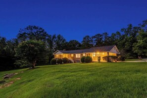 A two-story house with a well-maintained lawn and a driveway leading to the front door.
