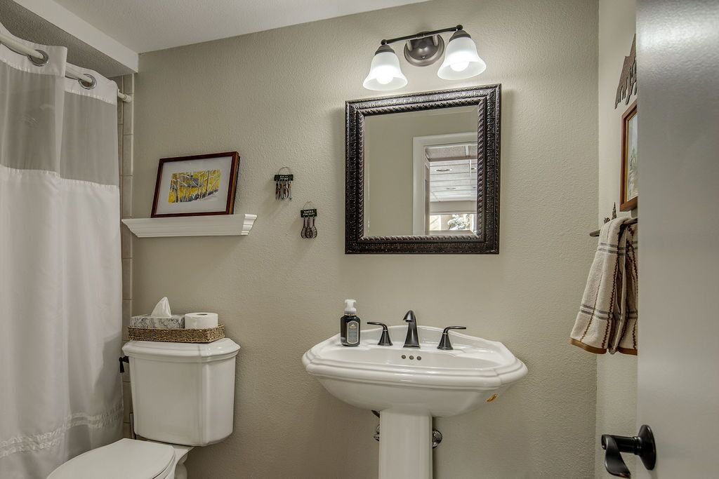 A bathroom with a white sink, a mirror, and a toilet.