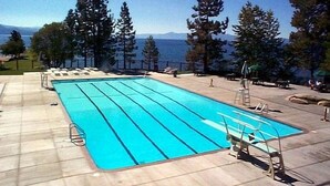 Une piscine rectangulaire à l’eau d’un bleu cristallin, entourée de chaises longues et dotée d’un plongeoir.