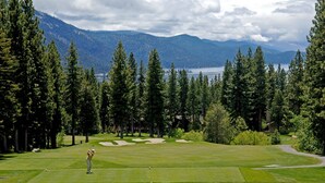 Un parcours de golf offrant une vue sur les montagnes et un lac.