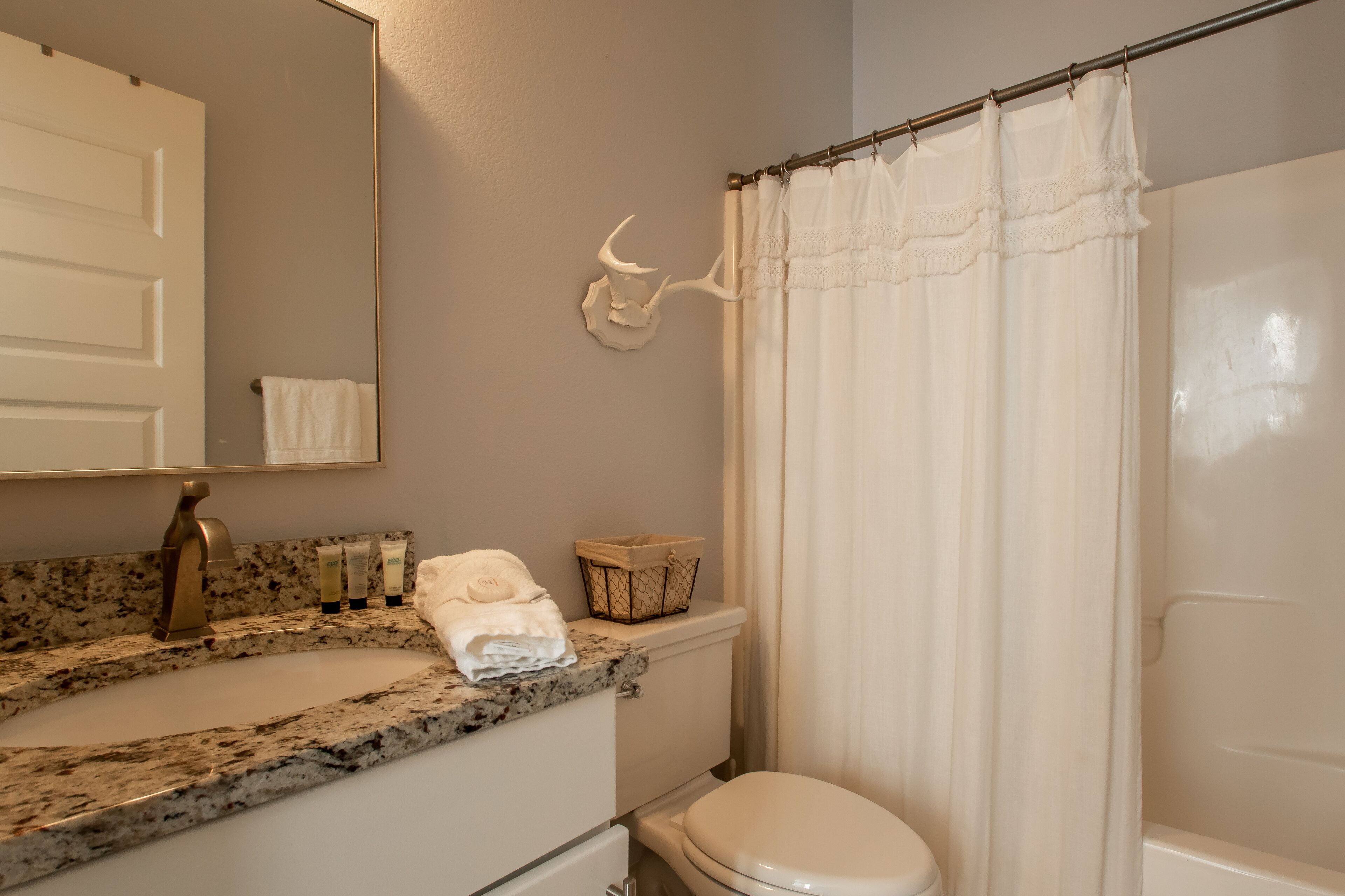 Une salle de bain avec un lavabo à vasque en granit, des toilettes blanches, un rideau de douche et un porte-serviettes.