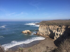 Eine Küstenlandschaft mit Sandstrand, Felsen und dem Meer.