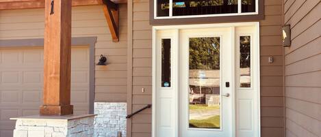 A house with a stone foundation, a wooden porch, and a garage door.