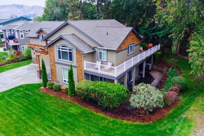 A two-story house with a balcony, a covered patio, and a well-maintained garden.