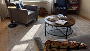 Un salon comprenant un canapé, un fauteuil, une table basse et une bibliothèque.