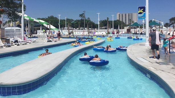 A swimming pool with multiple lanes and people using inflatable rings. - Beautiful Ocean Lakes Beach Home......100 Yards to the Beach. (Myrtle Beach)