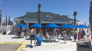 A beachside restaurant with outdoor seating and umbrellas. - Beautiful Ocean Lakes Beach Home......100 Yards to the Beach. (Myrtle Beach)