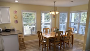 A kitchen with wooden cabinets, a dining table with chairs, and large windows with blinds. - Beautiful Ocean Lakes Beach Home......100 Yards to the Beach. (Myrtle Beach)