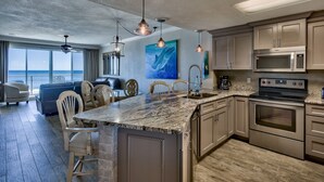 A modern kitchen with a large island, stainless steel appliances, and a view of the ocean. - 310 Sterling Sands Wake Up to Ocean Views in This Luxurious Beachfront Oasis! (Destin)