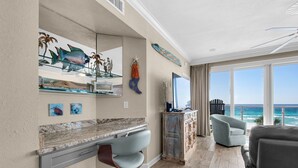 A modern living room with a large window, a desk, and a chair. - 310 Sterling Sands Wake Up to Ocean Views in This Luxurious Beachfront Oasis! (Destin)