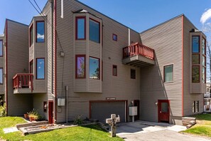 A multi-story building with a garage, a balcony, and a low clearance sign.