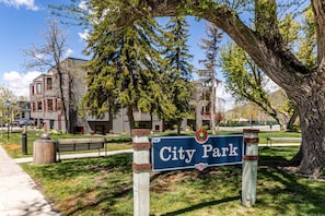 Placa com o nome 'City Park', um banco e árvores ao primeiro plano.