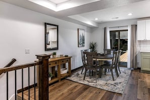 Uma área de refeições com mesa de madeira, cadeiras, um aparador e um tapete.