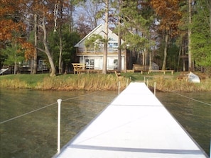 Enjoy waterfront views from this serene single-story house with a gabled roof, situated among mature trees.
