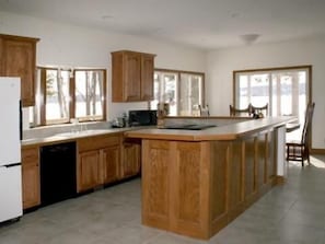Kitchen features a large island, wooden cabinetry, and a dishwasher, with a window and microwave.