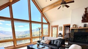 A spacious living room with a large window, a fireplace, and a ceiling fan. - Spectacular views and rural life, yet close to Boise (Boise)