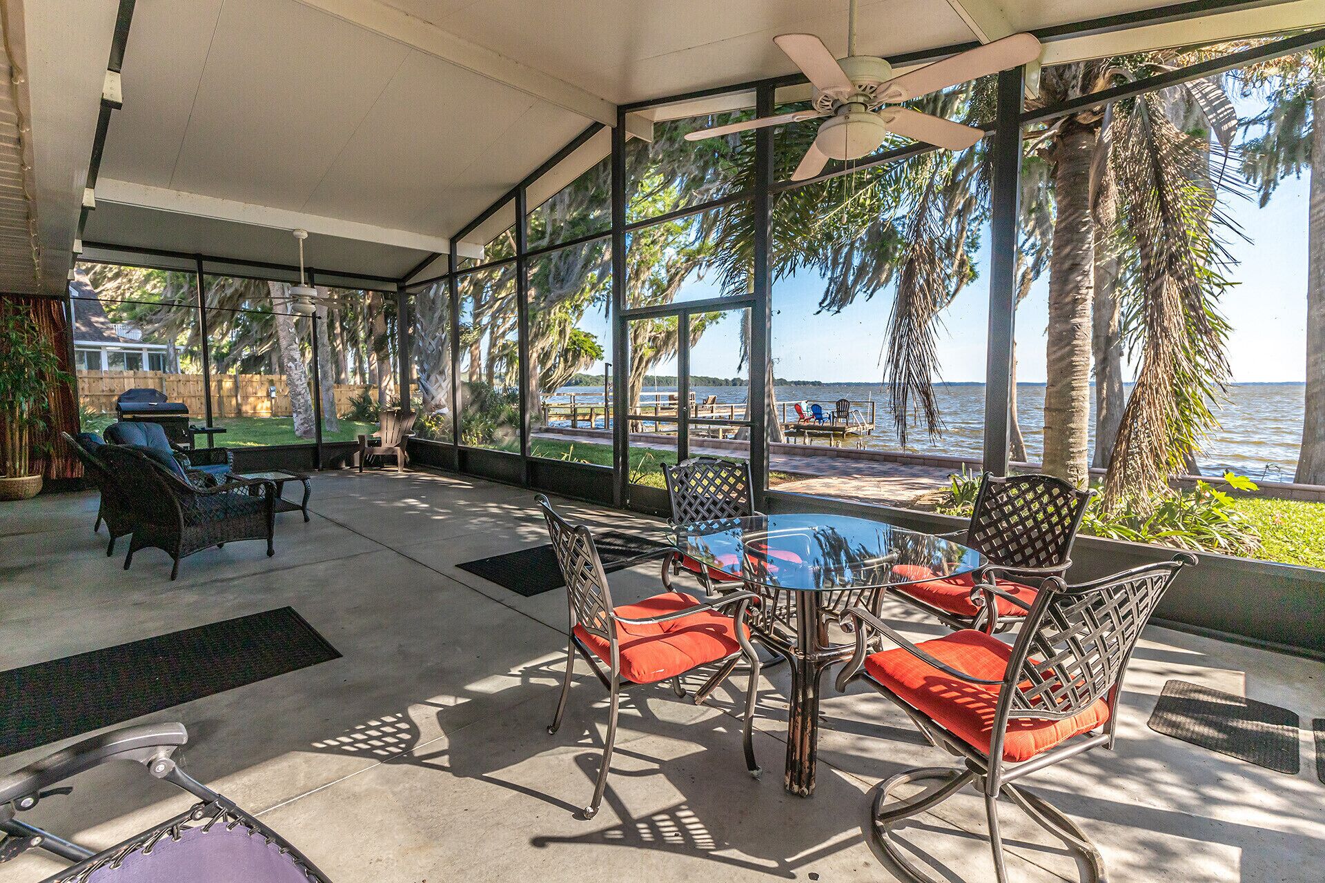 A covered patio with outdoor furniture, a ceiling fan, and a view of the water.