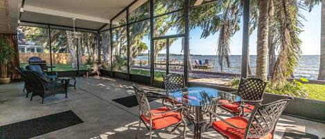 A covered patio with outdoor furniture, a ceiling fan, and a view of the water.