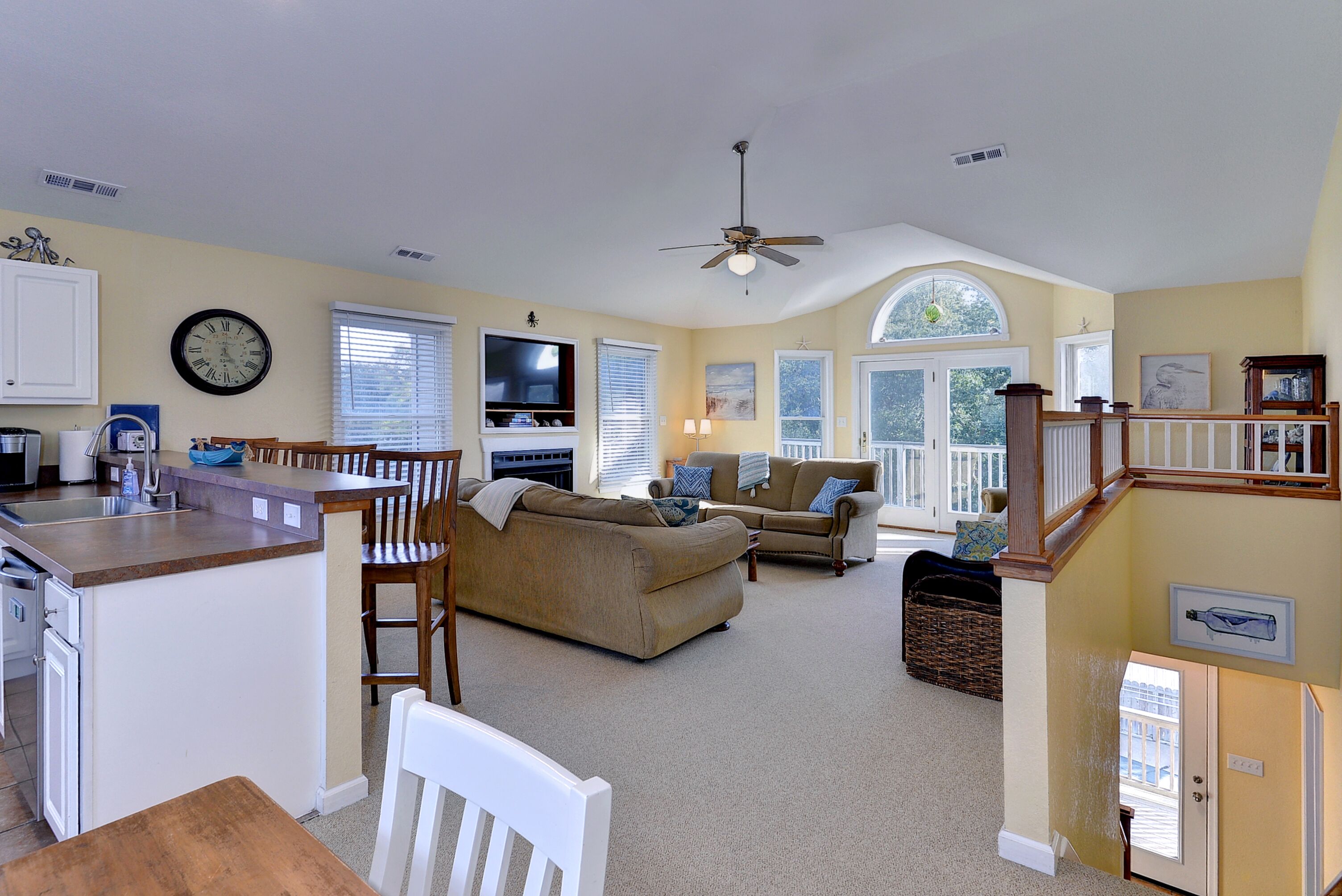A spacious living area with a kitchen, dining area, and a staircase leading to an upper level.