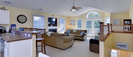 A spacious living area with a kitchen, dining area, and a staircase leading to an upper level.