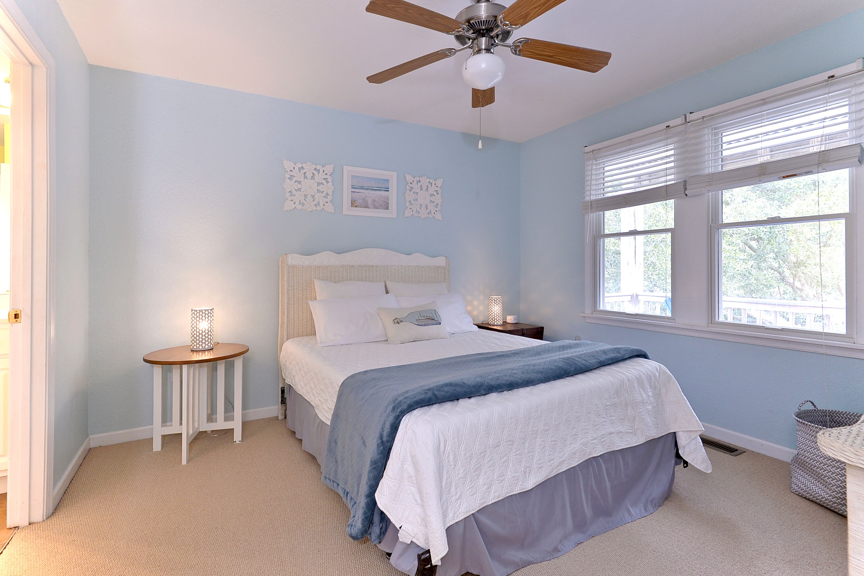 A bedroom with a bed, a bedside table, a ceiling fan, and a window with blinds.