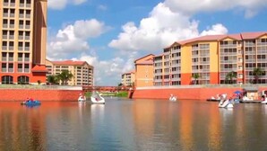 A waterfront hotel with multiple buildings, a calm river, and boats. - BEAUTIFUL RESORT STUDIO NEAR DISNEY (kissimmee)