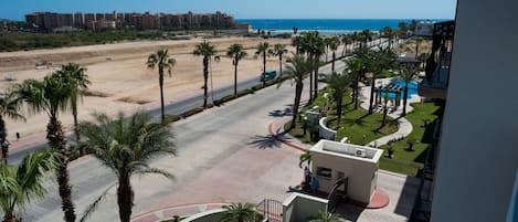 Un complexe hôtelier doté d’une piscine, de palmiers et offrant une vue sur la plage et l’océan.