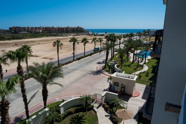 A resort with a pool, palm trees, and a view of the beach and ocean.