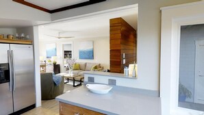 Una cocina moderna con horno integrado, una isla grande con un bol blanco y un área de estar con sofá y mesa de centro.