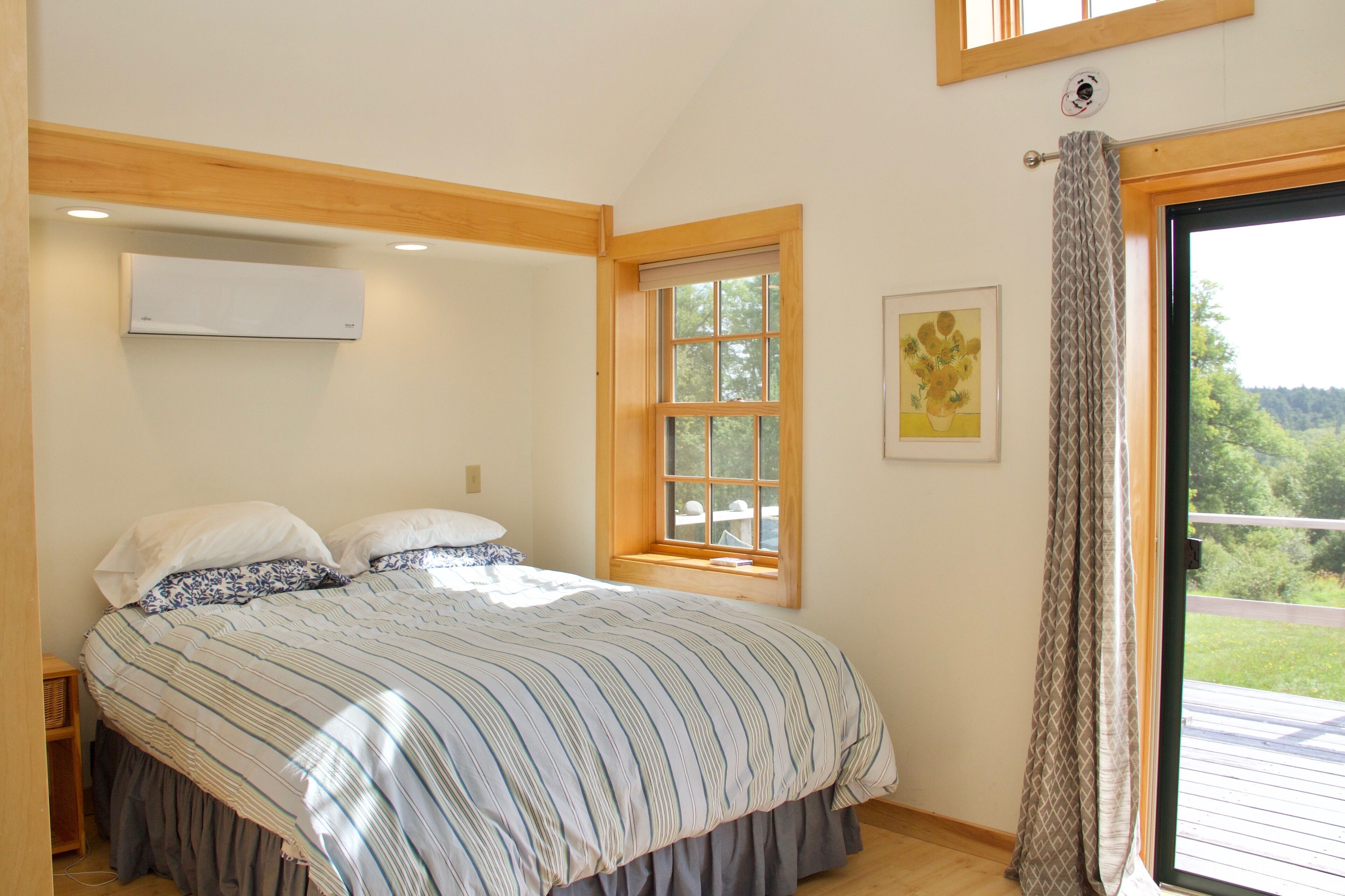 Un dormitorio con una cama grande, una ventana y vistas al verdor exterior.