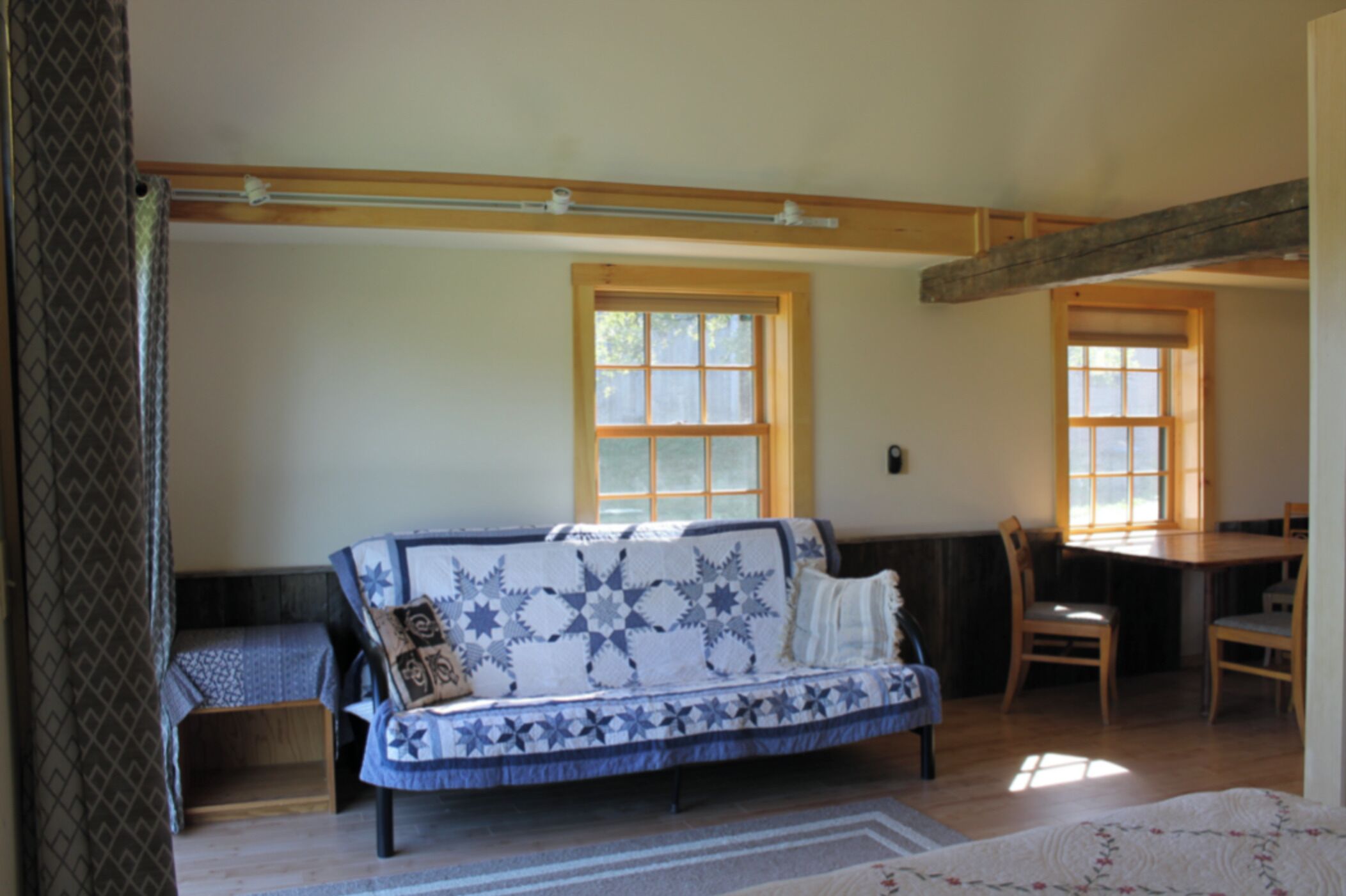 A cozy room with a blue and white patterned sofa, a small wooden table, and a window with a view of greenery.