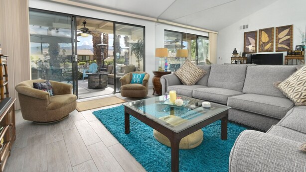 A spacious living room with a glass coffee table, grey sofa, and armchairs. - BEST in Monterey Country Club-South-New Remodel-2024-STR or monthly-185 Gran Via (Palm Desert)